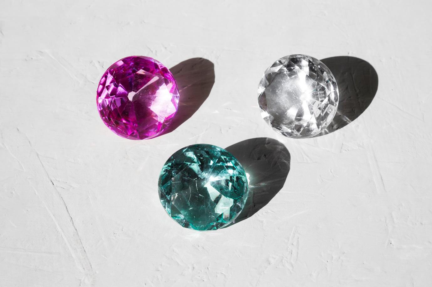 Assorted natural gemstones including diamonds, rubies, sapphires, emeralds, and pearls showcasing the unique beauty and imperfections of each stone.