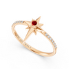 A rose gold ring featuring a starburst design with a central round red ruby gemstone and pavé-set clear stones along the band. The inside of the band is engraved with the brand name 'AUWL ASSEMBLY'.