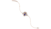 A delicate bracelet featuring a central owl charm with a blue sapphire gemstone face, surrounded by small clear stones, on a fine rose gold chain with a matching beaded extender.