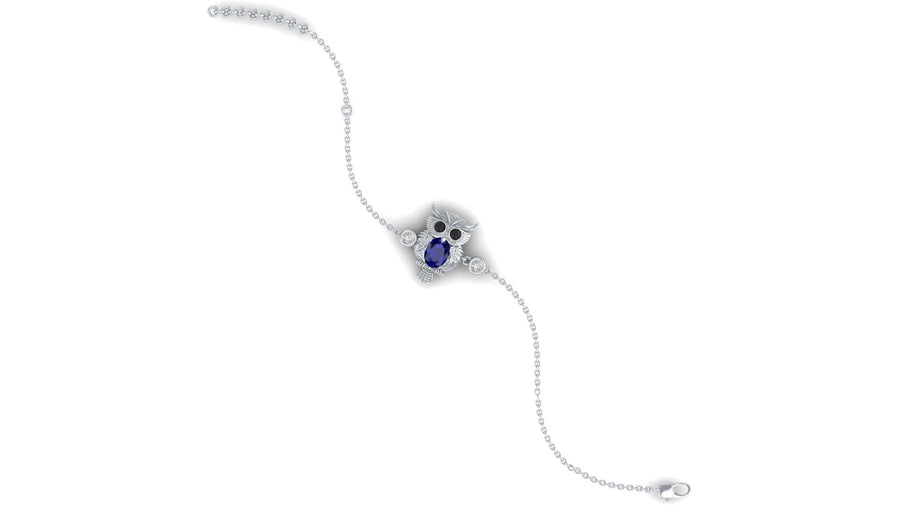 A delicate white gold bracelet featuring a central owl motif with a deep blue sapphire oval gemstone and small clear accent stones, shown on a plain white background.