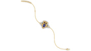 A delicate gold chain bracelet featuring a central owl charm with a deep blue sapphire oval stone for its eyes and small clear stones around it, displayed on a solid white background.
