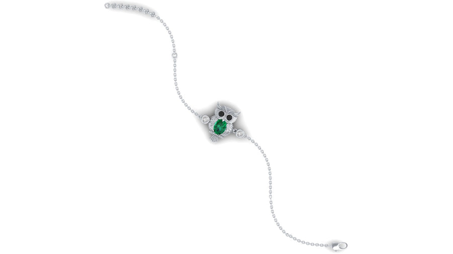 A delicate white gold chain bracelet featuring a central owl-shaped setting with a green oval gemstone and small clear accent stones, shown on a plain white background.