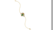 A delicate gold chain bracelet featuring a central owl-shaped charm with emerald gemstone and black eyes, set against a plain white background.