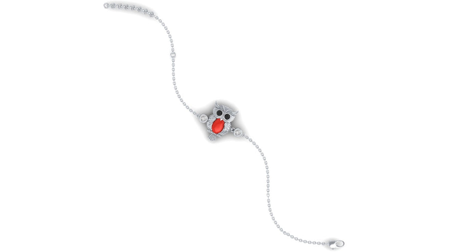 A delicate silver chain bracelet featuring a central owl charm with a bright red coral centrepiece and small clear stones around it, shown on a plain white background.