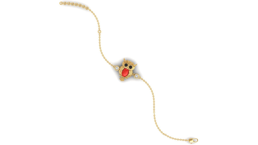 A delicate gold chain bracelet featuring a central owl-shaped charm with red coral gemstone and black eyes, set against a plain white background.