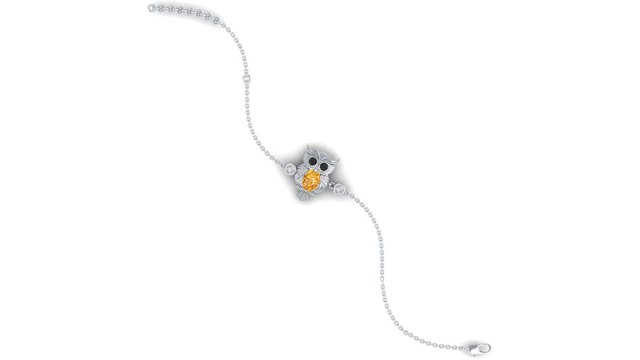 A delicate white gold bracelet featuring an owl charm with a yellow sapphire centrepiece and small clear stones, shown on a plain white background.