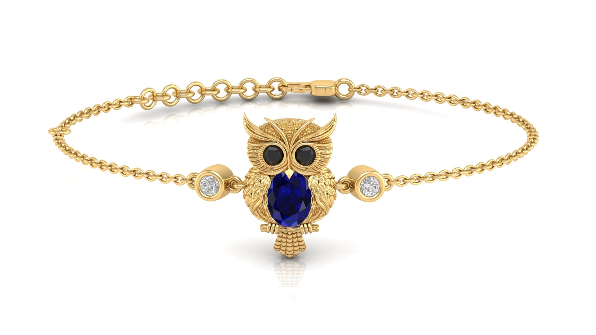 A gold chain bracelet featuring a central owl pendant with a large dark blue sapphire oval stone, black eyes, and small clear stones on either side, shown on a white background.