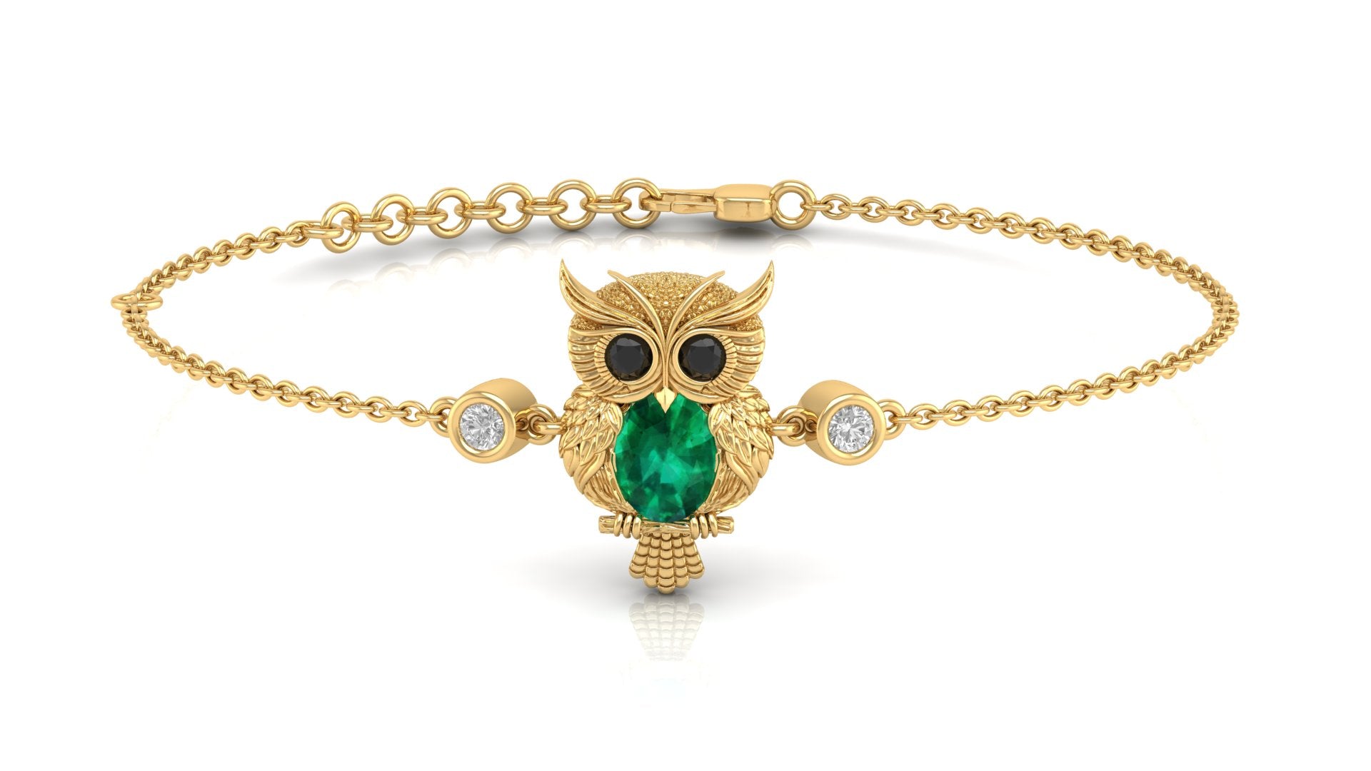 A gold chain bracelet featuring a central owl pendant with a green emerald-cut chest, black eyes, and small clear accent stones on either side, shown on a white background.
