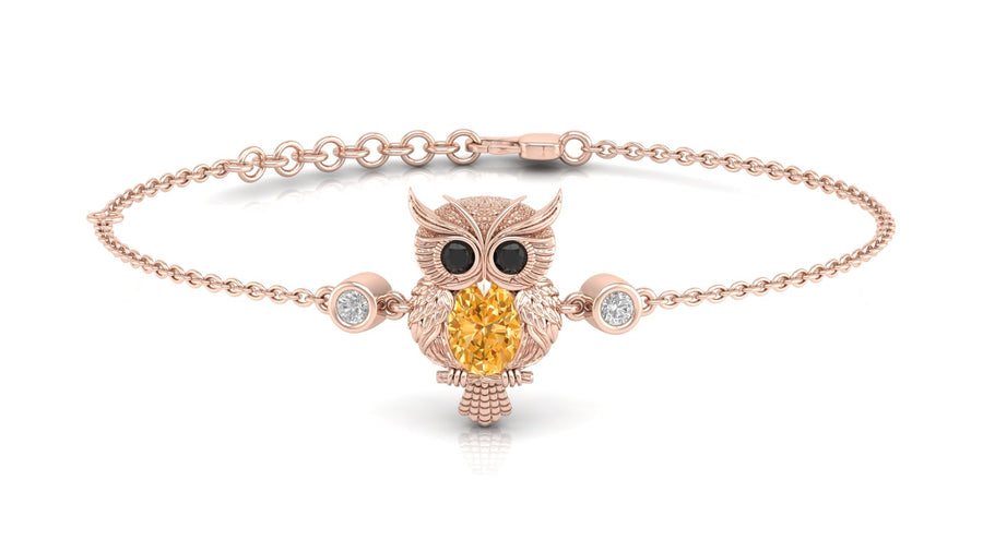 A delicate rose gold chain bracelet featuring an owl pendant with a large yellow sapphire center stone and small clear accent stones, shown on a clean white background.