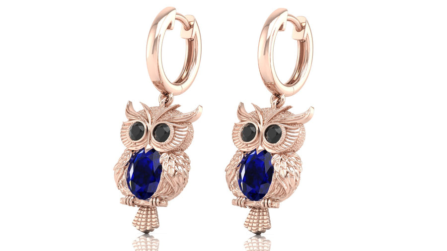 Rose gold owl earrings with blue sapphire gemstones on a white background