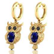 Gold owl-shaped earrings with Blue sapphire gemstones on a white background