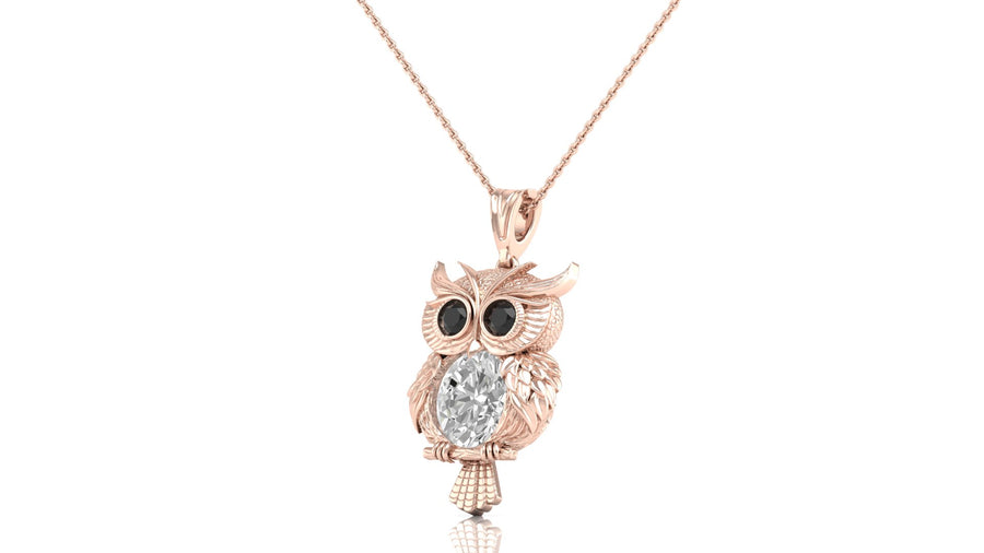 A rose gold owl pendant necklace featuring a large clear oval-cut diamond gemstone in the center and small black gemstone eyes, suspended from a delicate rose gold chain against a white background.