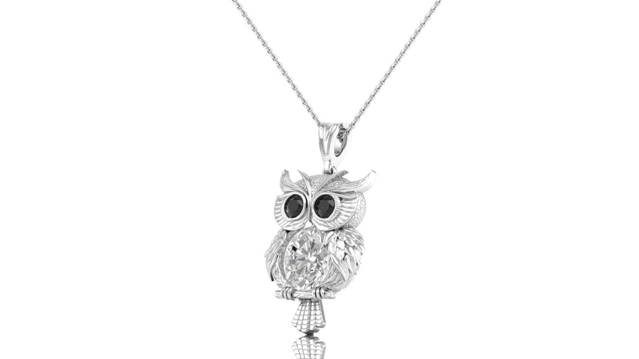 A white gold owl pendant necklace with black-stone eyes and a diamond centrestone, hanging from a delicate silver chain against a plain white background.
