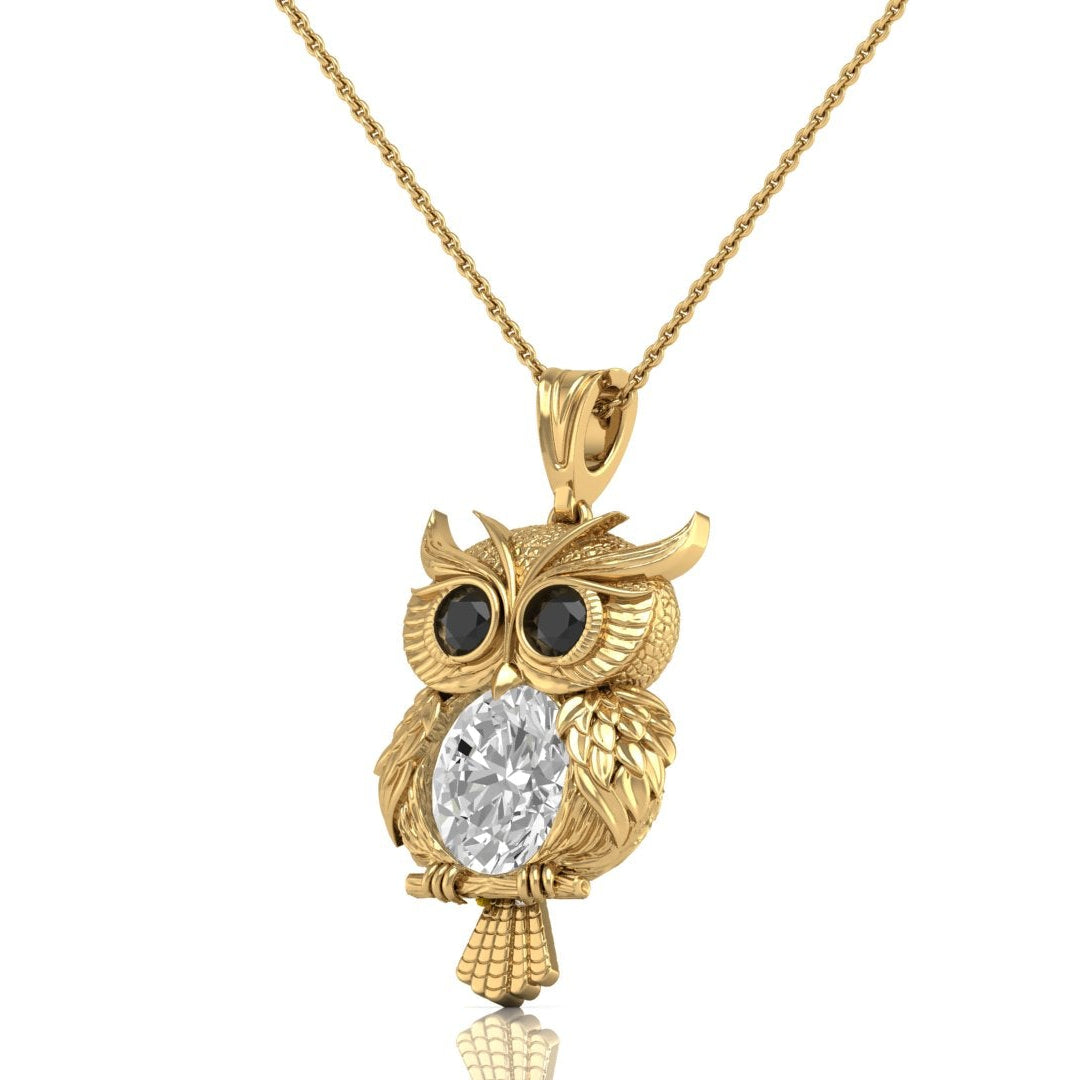A gold owl pendant necklace featuring a clear diamond oval cut center stone and dark round eyes, suspended from a delicate gold chain against a plain white background.