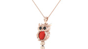 A rose gold owl pendant necklace featuring a textured owl body, large black eyes, and a prominent red coral oval chest detail, suspended on a delicate rose gold chain against a white background.