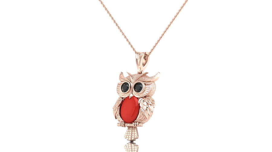 A rose gold owl pendant necklace featuring a textured owl body, large black eyes, and a prominent red coral oval chest detail, suspended on a delicate rose gold chain against a white background.