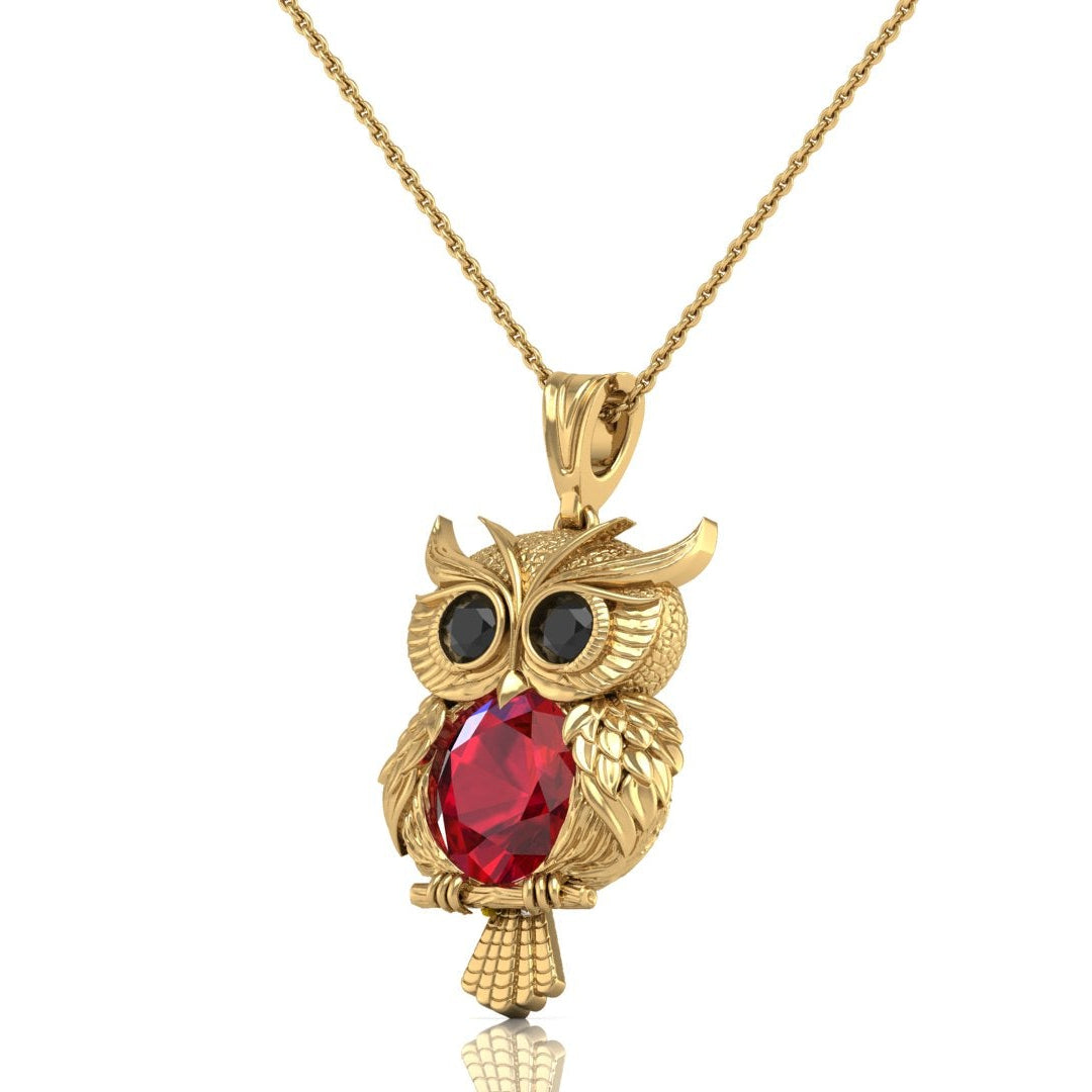 Gold owl pendant necklace with a large ruby gemstone in the center and black stone eyes, shown on a white background.