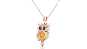 A rose gold owl pendant necklace featuring a large yellow sapphire on the center and black gemstone eyes, shown on a clean white background.