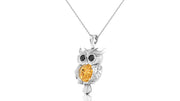 A white gold owl pendant necklace featuring a large oval yellow sapphire gemstone in the center, with black gemstone eyes, hanging from a delicate silver chain against a white background.