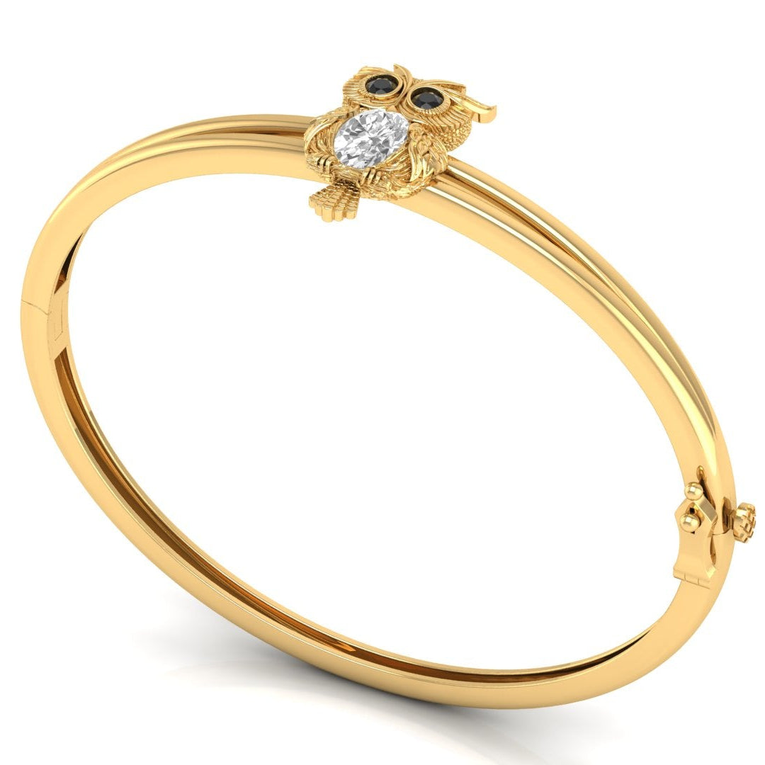 A gold bangle ring featuring a small owl charm with a clear central Diamond gemstone and dark eyes, displayed on a clean white background.