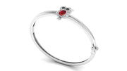 A white gold bangle bracelet featuring a small owl charm with a red ruby gemstone and dark eyes, set against a plain white background.