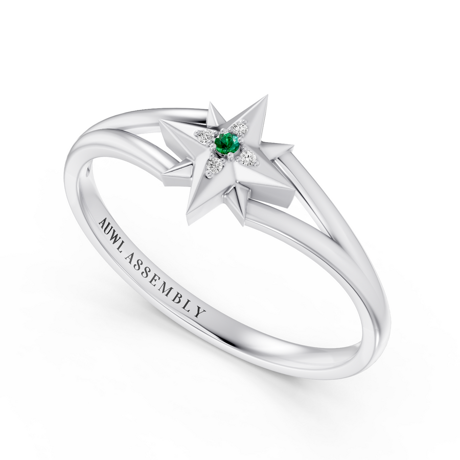A white gold star ring with a central green emerald and small clear stones, shown on a clean white background. The inside of the band is engraved with 'AUWL ASSEMBLY'.