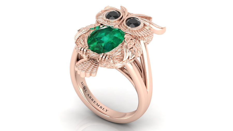 Rose gold ring with emerald and black gemstones on a white background