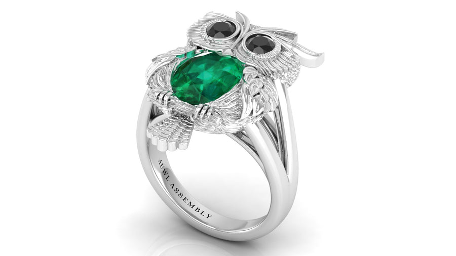 White Gold owl-shaped ring with emerald and black gemstones on a white background