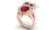 Rose gold ring with a ruby and black gemstones on a white background