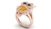 Rose gold ring with yellow sapphire and black gemstones on a white background
