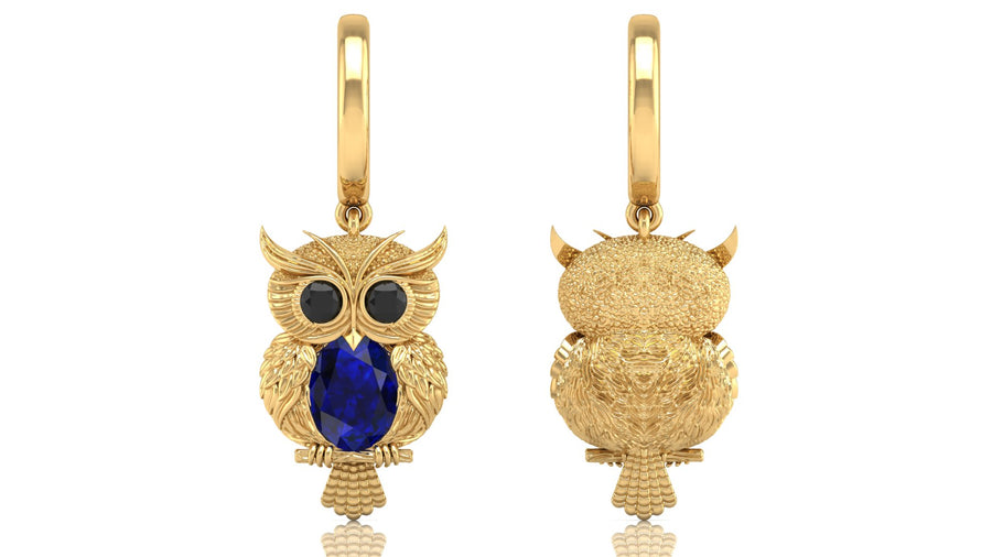 Gold owl-shaped earrings with blue sapphire gemstones on a white background