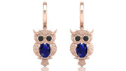 Rose gold owl earrings with blue sapphire gemstones on a white background