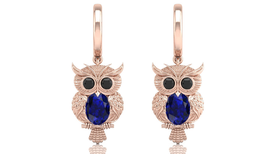 Rose gold owl earrings with blue sapphire gemstones on a white background