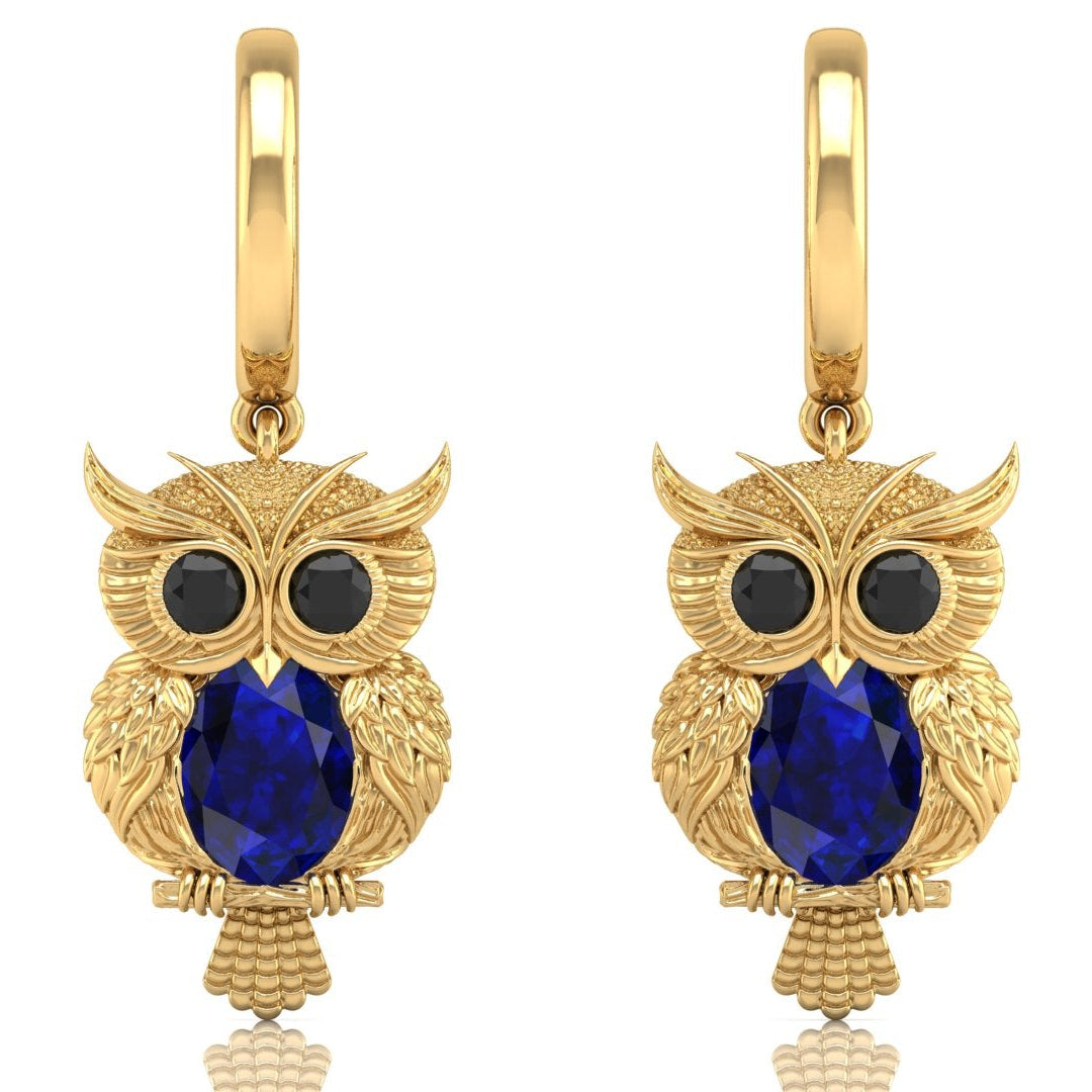 Gold owl earrings with blue sapphire gemstones on a white background