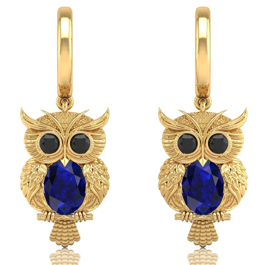 Gold owl earrings with blue sapphire gemstones on a white background