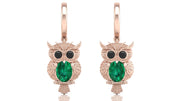 Rose gold owl earrings with green gemstones on a white background