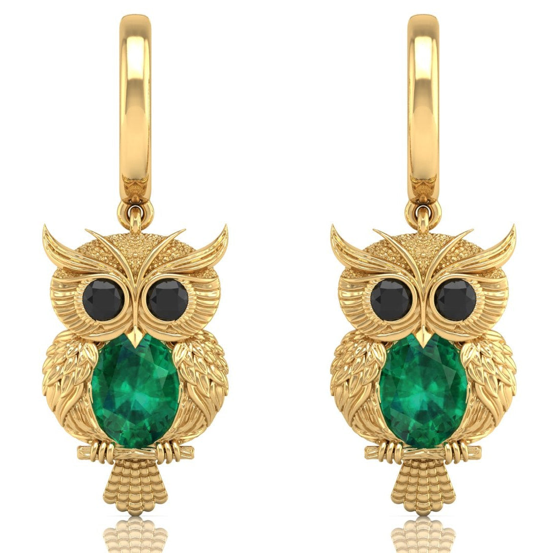 Gold owl earrings with emerald green gemstone on a white background