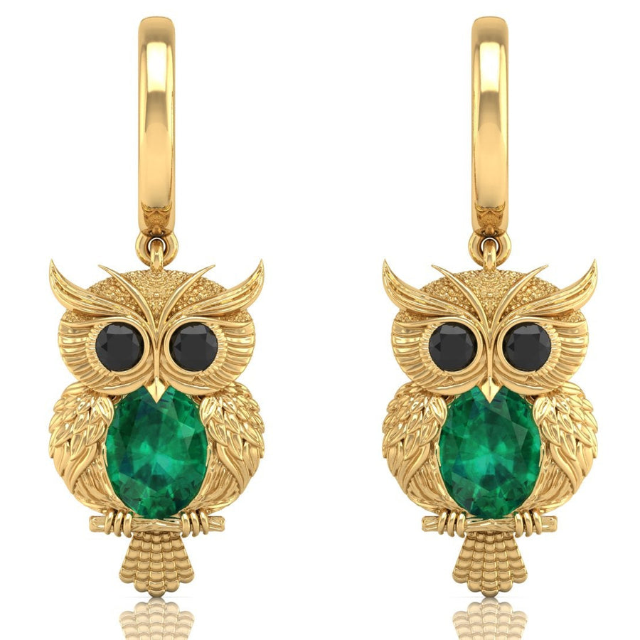 Gold owl earrings with emerald green gemstone on a white background