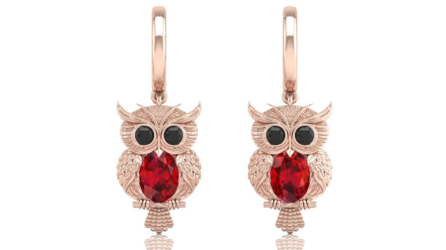 Rose gold owl earrings with ruby gemstones on a white background