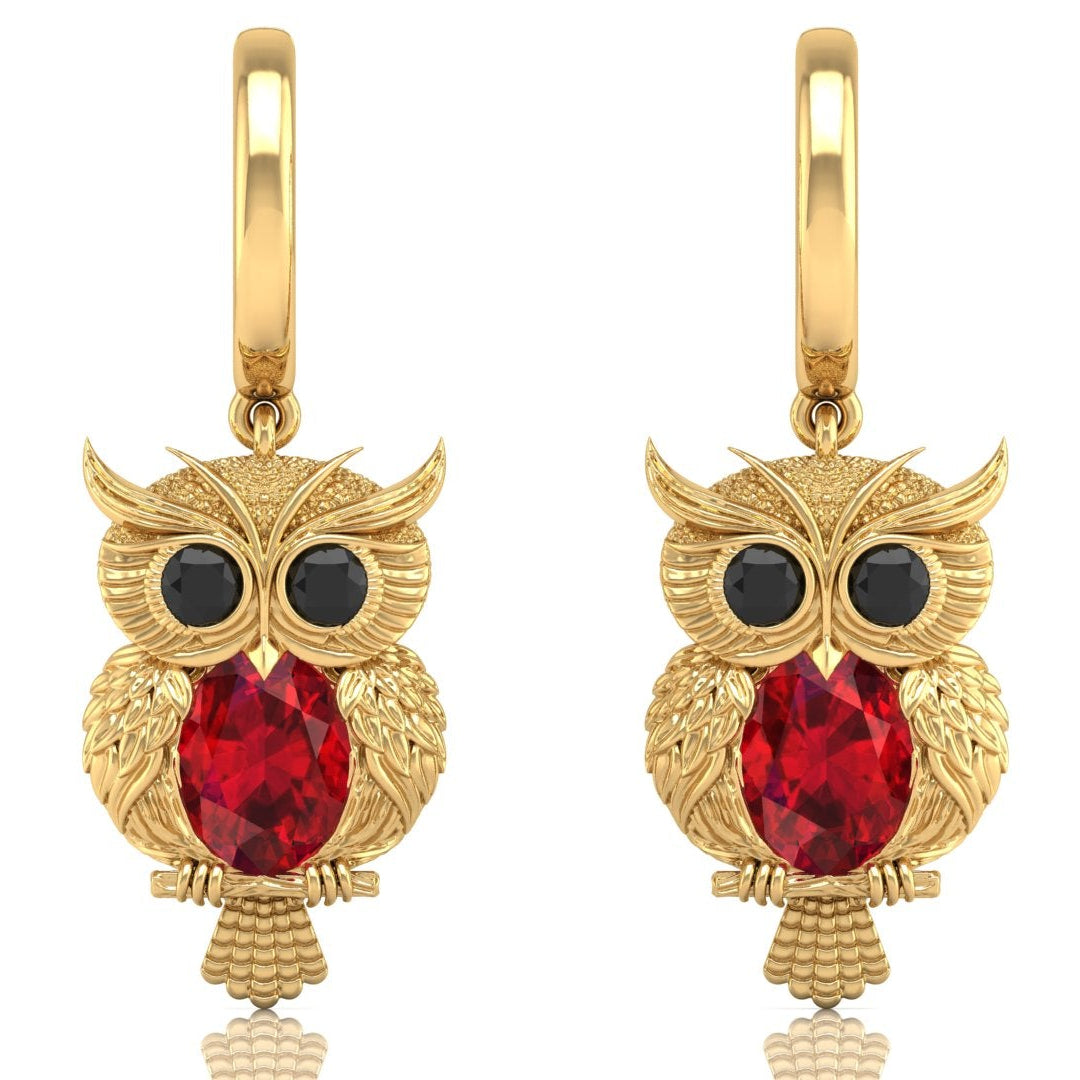 Gold owl earrings with ruby gemstones on a white background
