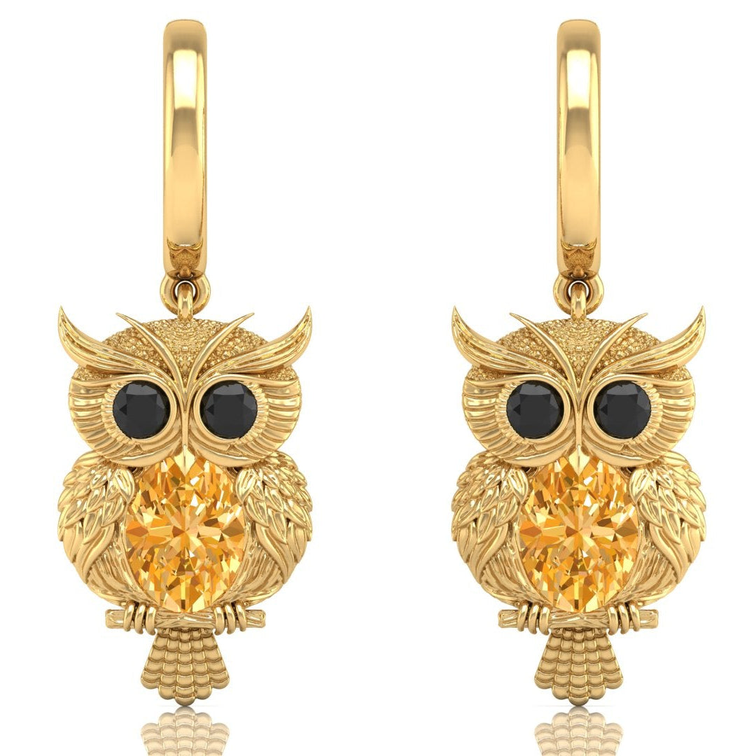 Gold owl earrings with yellow sapphire gemstones on a white background