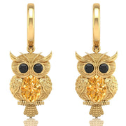 Gold owl earrings with yellow sapphire gemstones on a white background