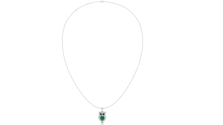 A delicate white gold necklace featuring an owl pendant with a vibrant green emerald centrestone details, set against a plain white background.