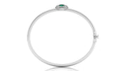 A polished white gold bangle bracelet with a small oval green gemstone and surrounding clear stones at the top, shown on a plain white background.