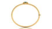 A yellow gold hinged bangle bracelet with a small green oval gemstone and gold detailing at the top, shown on a plain white background.
