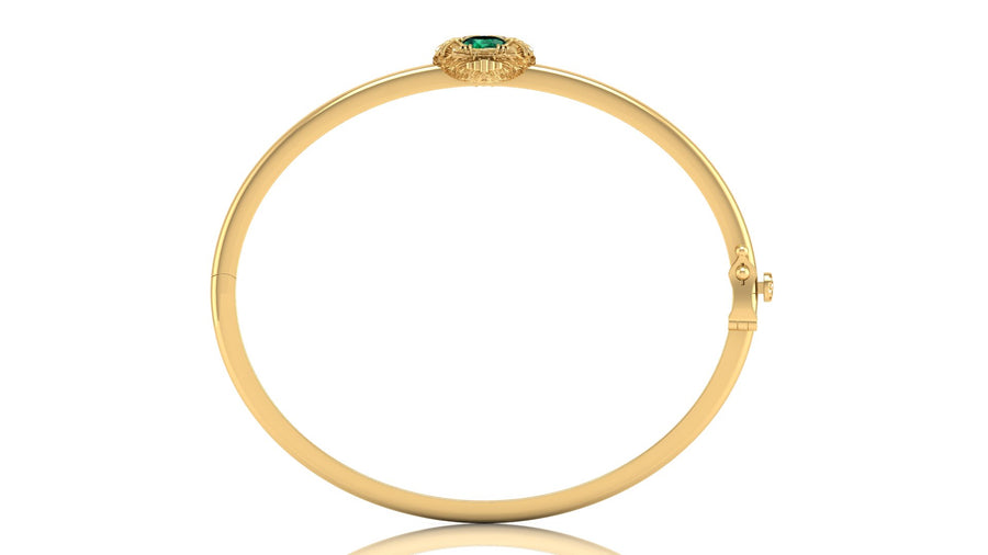 A yellow gold hinged bangle bracelet with a small green oval gemstone and gold detailing at the top, shown on a plain white background.
