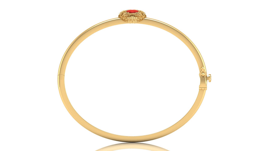 A gold bangle bracelet with a small red coral centre stone and gold detailing at the top, shown on a plain white background.