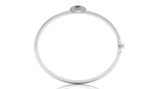 A polished white gold bangle bracelet with a small oval red ruby gemstone at the top, shown on a plain white background.