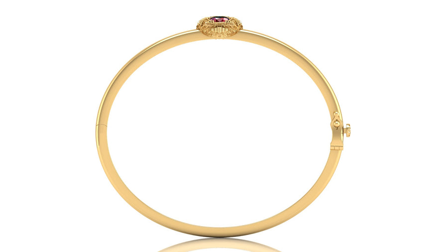 A yellow gold hinged bangle bracelet with a small oval ruby gemstone set in a textured bezel at the top, shown on a plain white background with a subtle reflection.