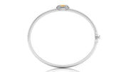 A polished white circular bangle bracelet with a small oval yellow sapphire gemstone and surrounding clear stones at the top, shown on a white background.